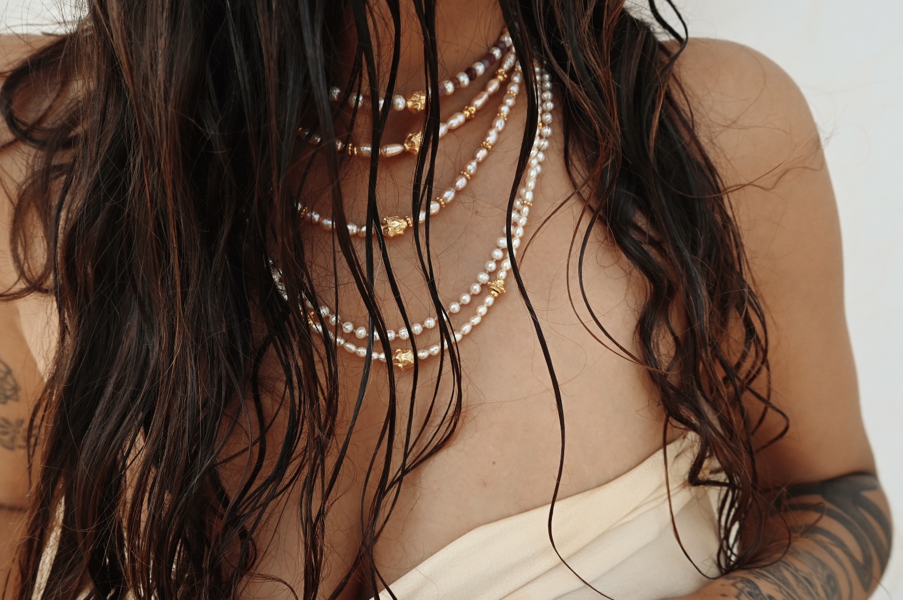 Layered handmade pearl and gold necklaces by Akasha, worn against wet hair